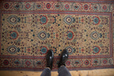 Vintage Tabriz runner's worn field featuring palmette and blossom motifs in sand, blue, and red.