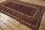 Vintage Kurd rug viewed from the corner, displaying its staggered boteh field and intricate geometric borders.