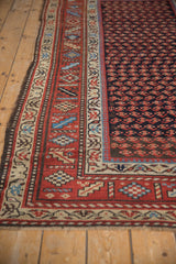 Angled view of a vintage Kurd rug's rust border with geometric blossoms and dark selvage.