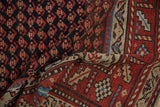 Hand-knotted texture of a vintage Kurd rug, contrasting the navy boteh field and rust border.
