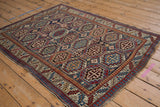 Angled view of a vintage Moghan Kazak rug showing its repeating octagonal gul pattern.