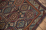 Corner view of a vintage Caucasian rug highlighting its geometric guls and worn texture.