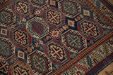 Close view of the geometric octagonal guls and low-pile texture of a vintage Caucasian rug.