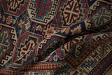 A vintage Caucasian rug's supple, hand-knotted body showing even wear and geometric guls.