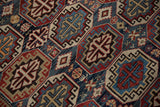 A detailed view of the low-pile texture and repeating octagonal guls of a vintage Caucasian rug.