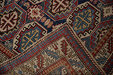 Folded corner of a vintage Caucasian rug reveals its hand-knotted back and geometric pattern.