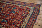 The intricate pawn and floral motif borders and tattered edge of an antique Caucasian Seichour rug.