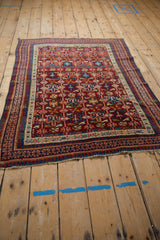 Angled view of an antique Caucasian rug highlighting its elaborate geometric field and multi-layered borders.