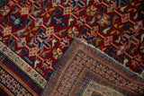 Antique Caucasian rug corner folded back, revealing the detailed hand-knotted foundation.