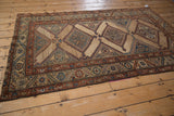 An antique Kurd rug with a geometric design of repeating diamond medallions shown from an oblique angle.