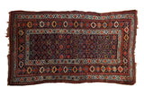 Vintage Kurd rug with a navy field of geometric starburst florals, framed by intricate, colorful borders.