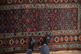 Overhead perspective on the Kurd rug's field of starburst motifs and floral borders.