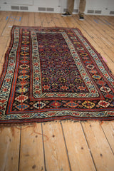 A vintage Kurd rug from an angle, showcasing its intricate geometric field and multi-banded borders.