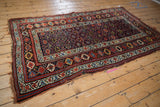Angled view of a Kurd rug showing the serrated geometric field and meandering vine borders.