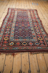 An angled view down the length of a vintage Kurd rug with geometric starburst floral motifs.