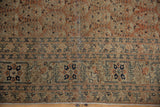 Antique Tabriz rug's ornate floral border and intricate boteh field in terracotta, ivory, and navy, with historic patina.