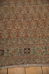Antique Tabriz rug's meandering vine floral border and fringe in pale copper and navy.