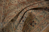 Folded antique Tabriz rug detailing intricate terracotta botehs, floral border, and worn pile.