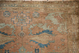 Distressed vintage Malayer rug detail, showing low pile, blue geometric patterns, and copper-terracotta field.