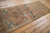 Distressed Malayer rug runner corner, showing faded copper and blue field with fringed edge.