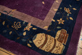 Vintage Nichols carpet corner detail: navy border with gold cloudband vase motif, plum field.