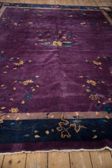 Aubergine field with pale gold vinery and blossoms, navy blue border with fringe.
