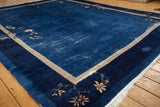 Peking carpet corner: indigo field with wear, beige stripe, and blossom design.