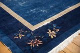 Peking carpet corner: indigo blue field with wear, beige border, and delicate floral vinery.