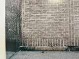 Close-up of the color photograph showing the gritty textures of a gray brick wall and concrete sidewalk corner.
