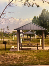 Color photograph of a park in Provo, Utah, with picnic shelters against a backdrop of hazy mountains.