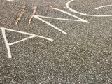 Granular asphalt texture with abstract, faded white letterforms and marks.