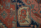 Detail of an antique Serapi carpet, with madder red field, navy border, and teal palmettes.