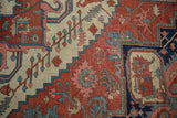 Detail of antique Serapi carpet showing navy turtle samovar border and madder red field palmettes.
