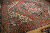 Polychromatic side cord on antique Serapi carpet corner with madder red and navy motifs.