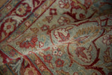 Distressed Yezd rug's floral vinery pattern in pale blue, raspberry, and dusty gold.