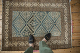 Distressed Malayer rug detail showing blue and beige geometric starbursts and patterned floral borders.