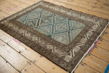 Distressed vintage Malayer rug corner, featuring dusty blue starburst panels and chocolate brown floral border.