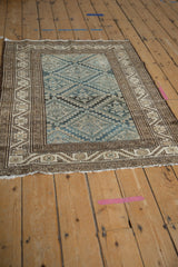 Distressed Malayer rug corner, showing blue starburst field, geometric floral borders, and secured edge.