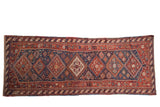 Antique Persian Afshar runner with a single column of diamond-shaped medallions in cherry red and cobalt blue.