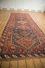 A perspective view down the length of an antique Afshar runner showing its column of medallions.