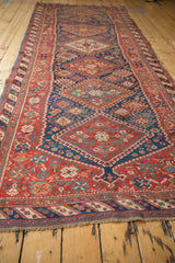 Antique Afshar runner seen from a low angle, emphasizing its length and column of diamond medallions.