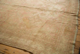 Soft, distressed pile of vintage Oushak rug with muted beige and dusty rose.