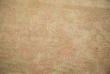 Vintage distressed Oushak pile with soft beige and blush pink patterned areas.