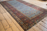 Angled view of an antique Fereghan carpet highlighting its powder blue field against a wide, madder root red border.
