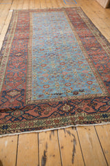 The wide, banded main border of an antique Fereghan carpet framing its long, powder sky blue Herati field.