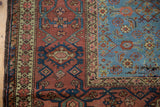 Intricate serpent and starburst minor border alongside the wide madder red main border of a Fereghan carpet.
