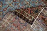 Detail of antique Fereghan rug's corner showing the hand-knotted reverse and intricate starburst border.