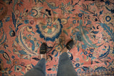 Vintage Laristan carpet with allover dusty rose, navy, and teal scrolled vines, seen underfoot.