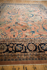 Vintage Laristan carpet's navy border and dusty rose field with scrolled vines and blossoms.
