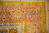 Vintage Oushak rug corner detail with saffron yellow border and blush floral palmettes.